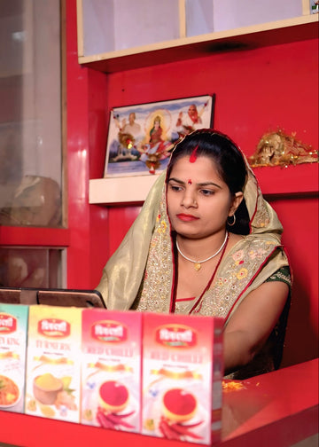 Woman behind a counter with various products and a red wall.